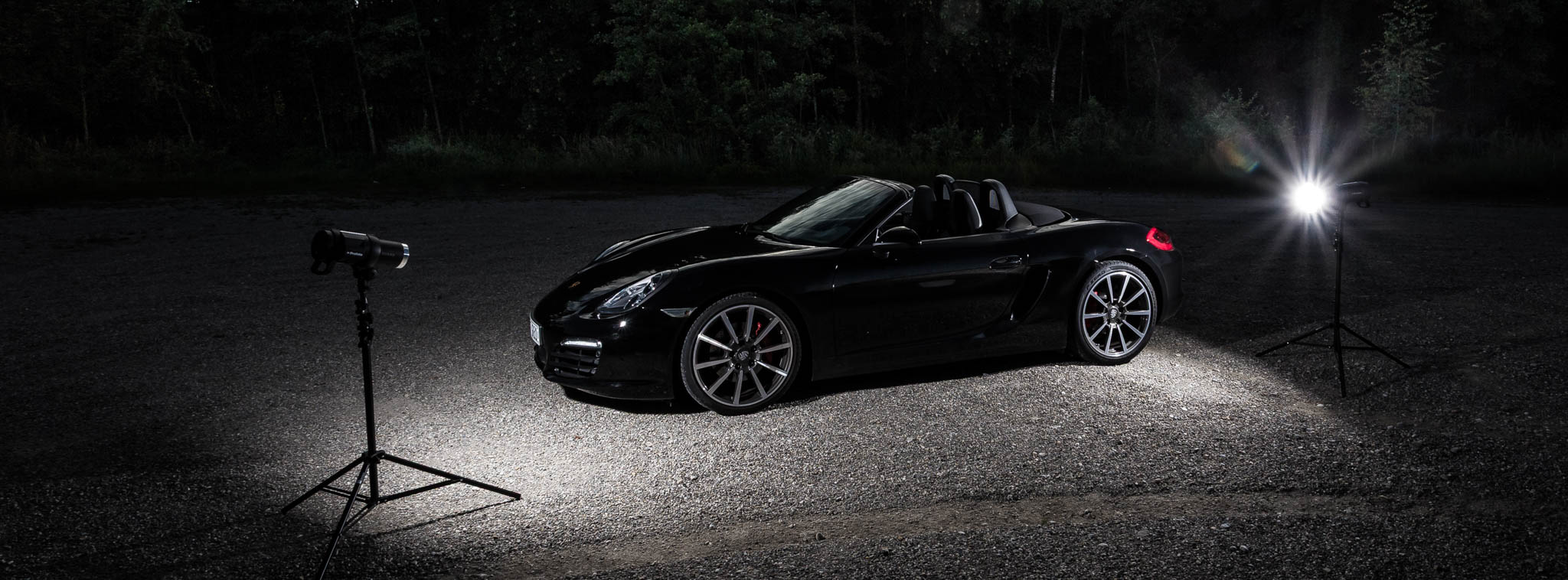 Convertible sports car parked under studio lights on a dark outdoor setting.