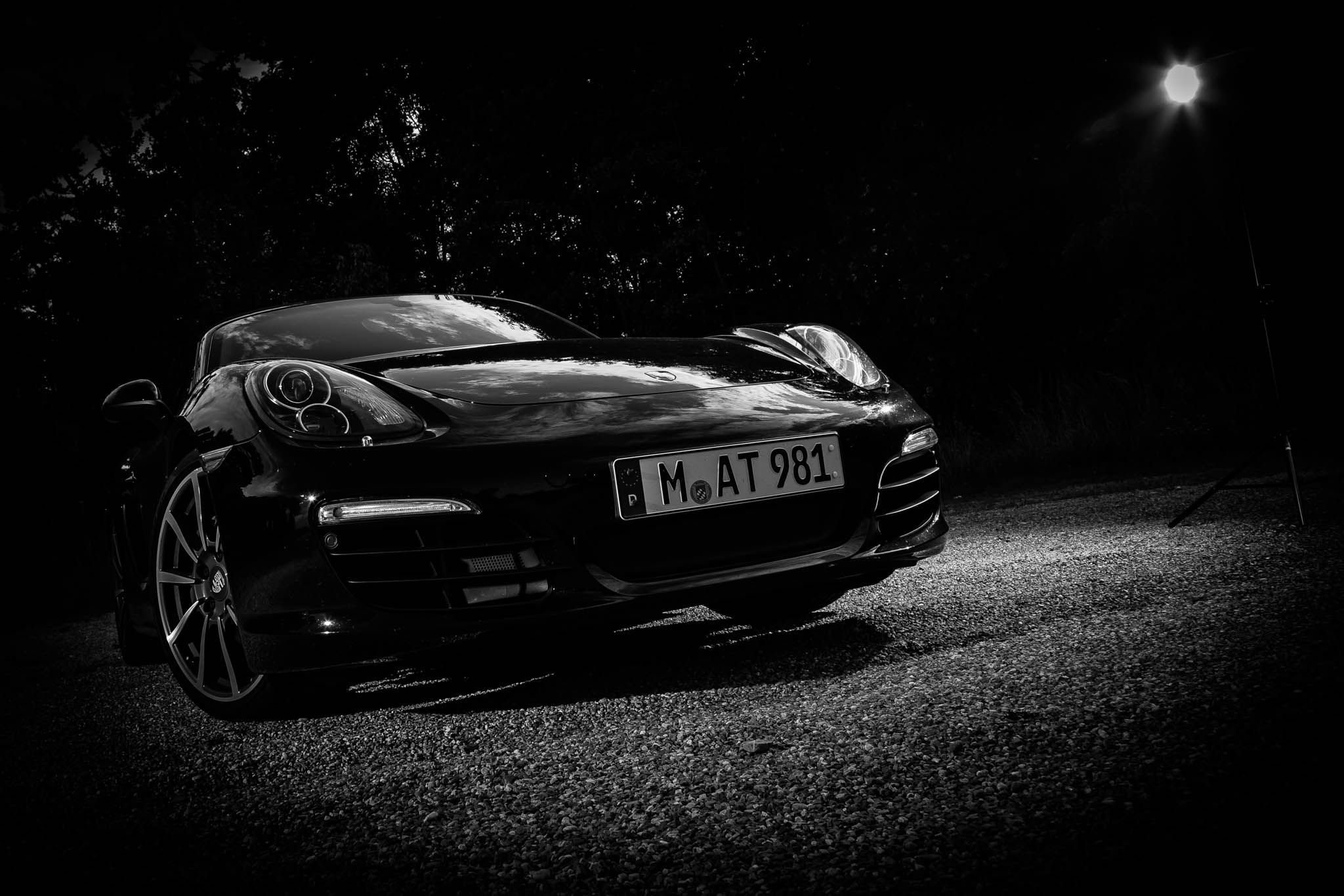 Black sports car with headlights on, parked in low light, highlighting sleek design and license plate M AT 981.