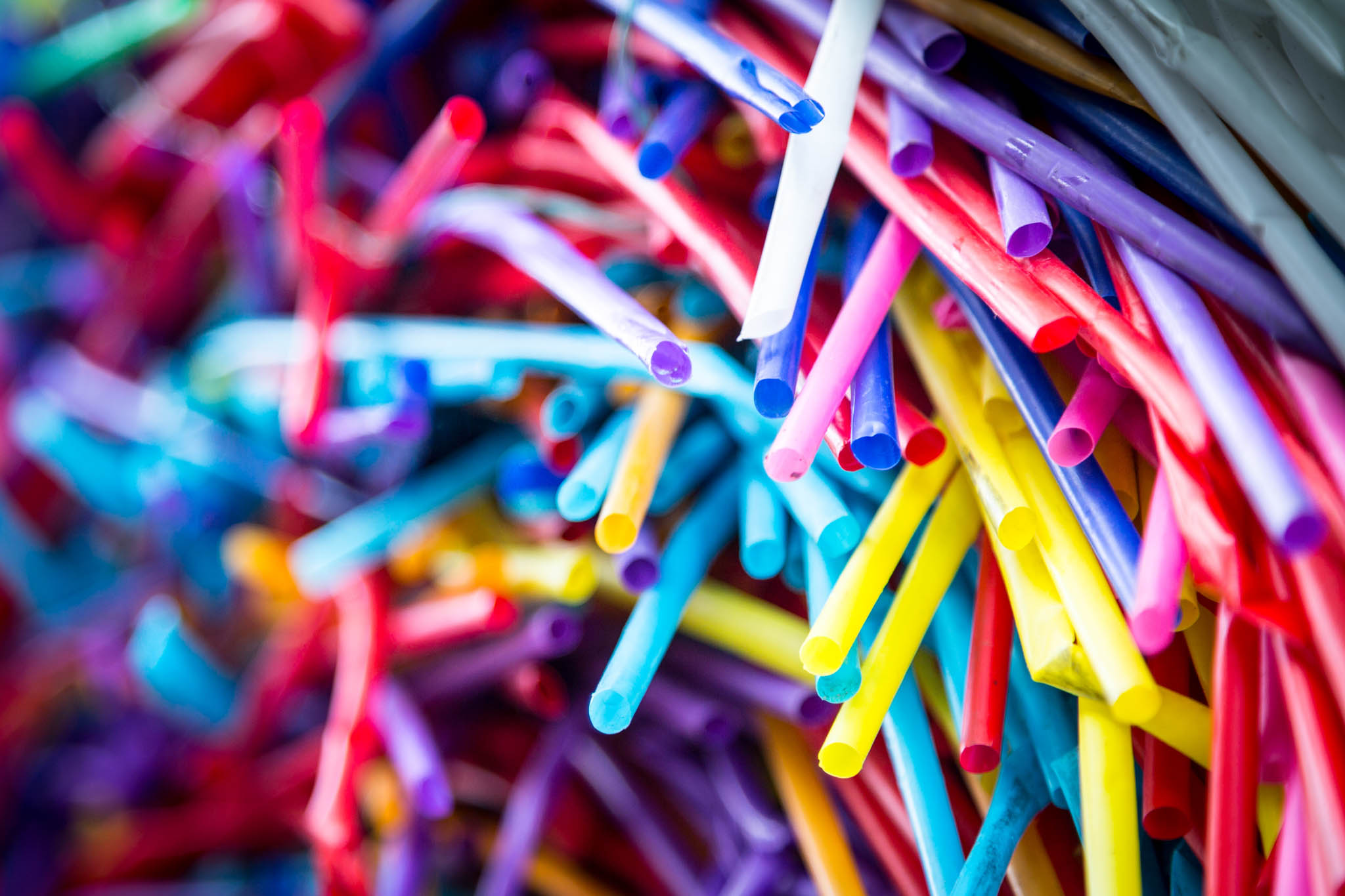 Close-up of colorful plastic straws in various shades, creating a vibrant and chaotic pattern.