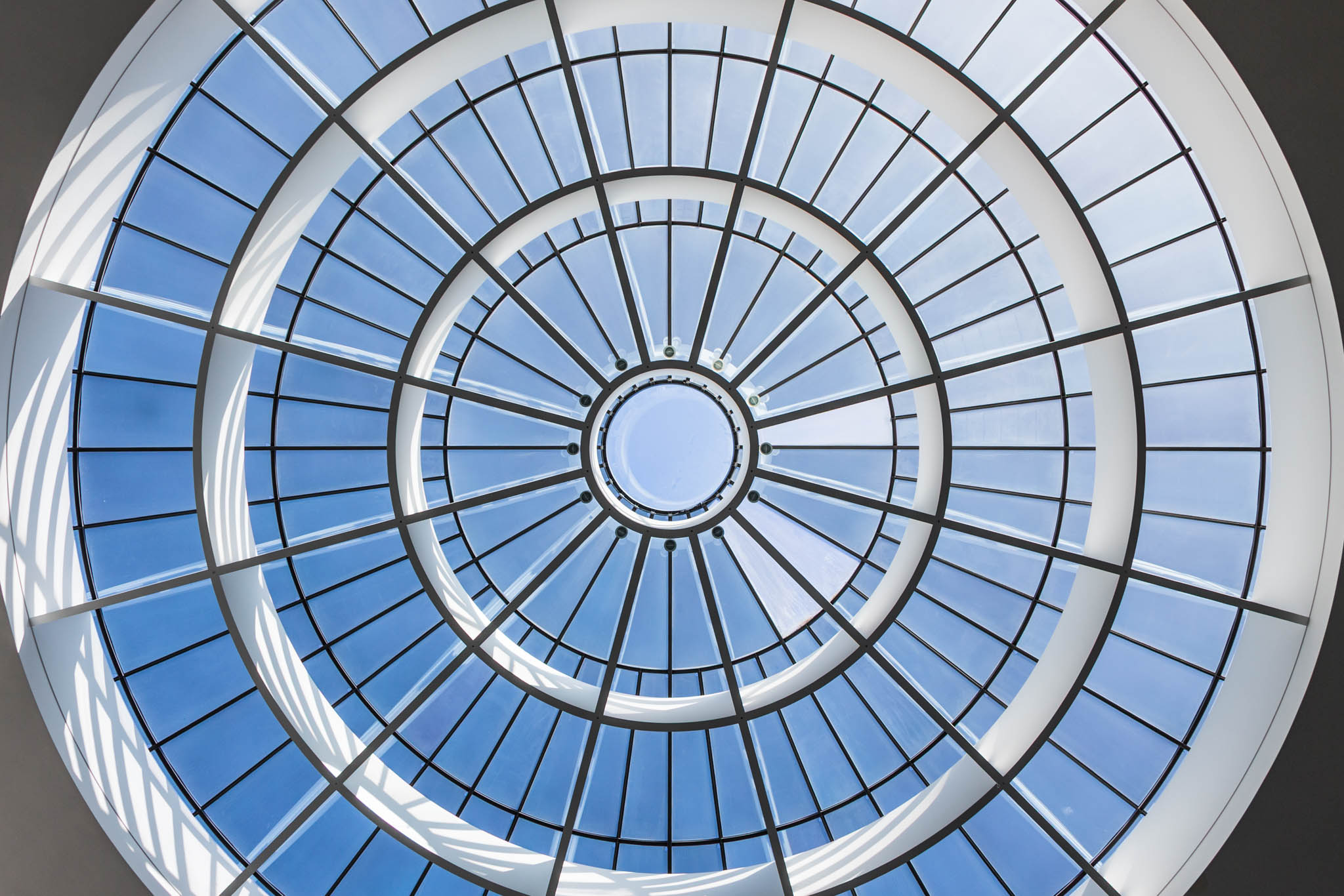 Circular glass dome ceiling with blue sky visible through radial metal frames.