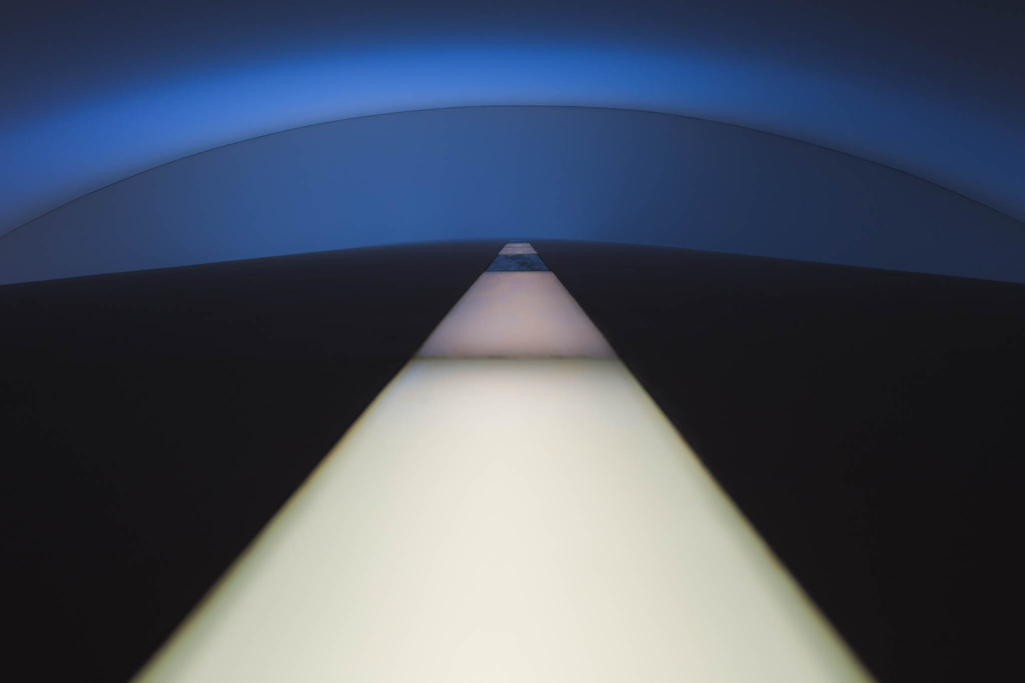 Abstract light installation with a glowing line and a curved blue background.