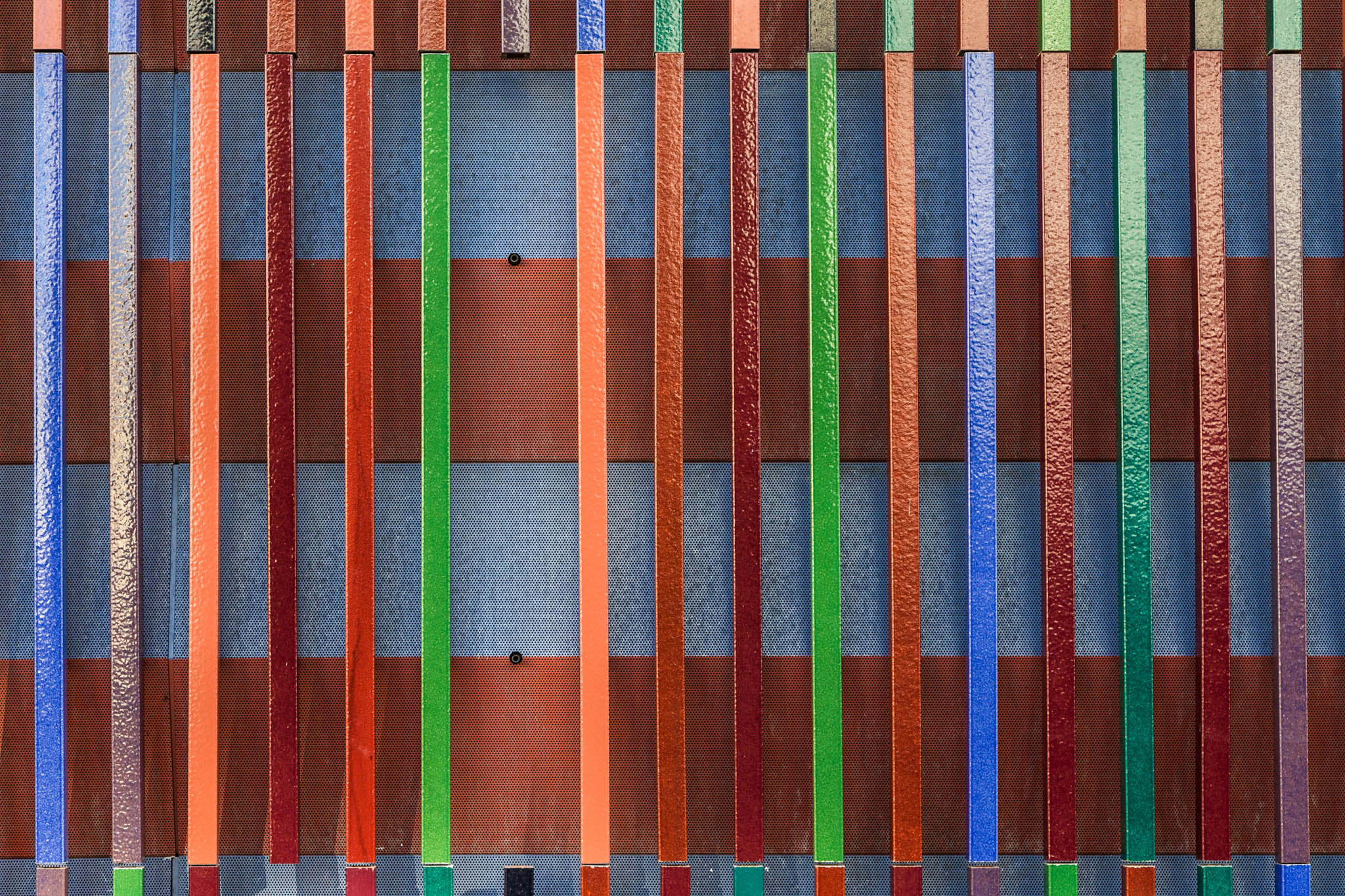 Colorful vertical stripes form a vibrant abstract pattern with textured and alternating blue, red, orange, and green tones.