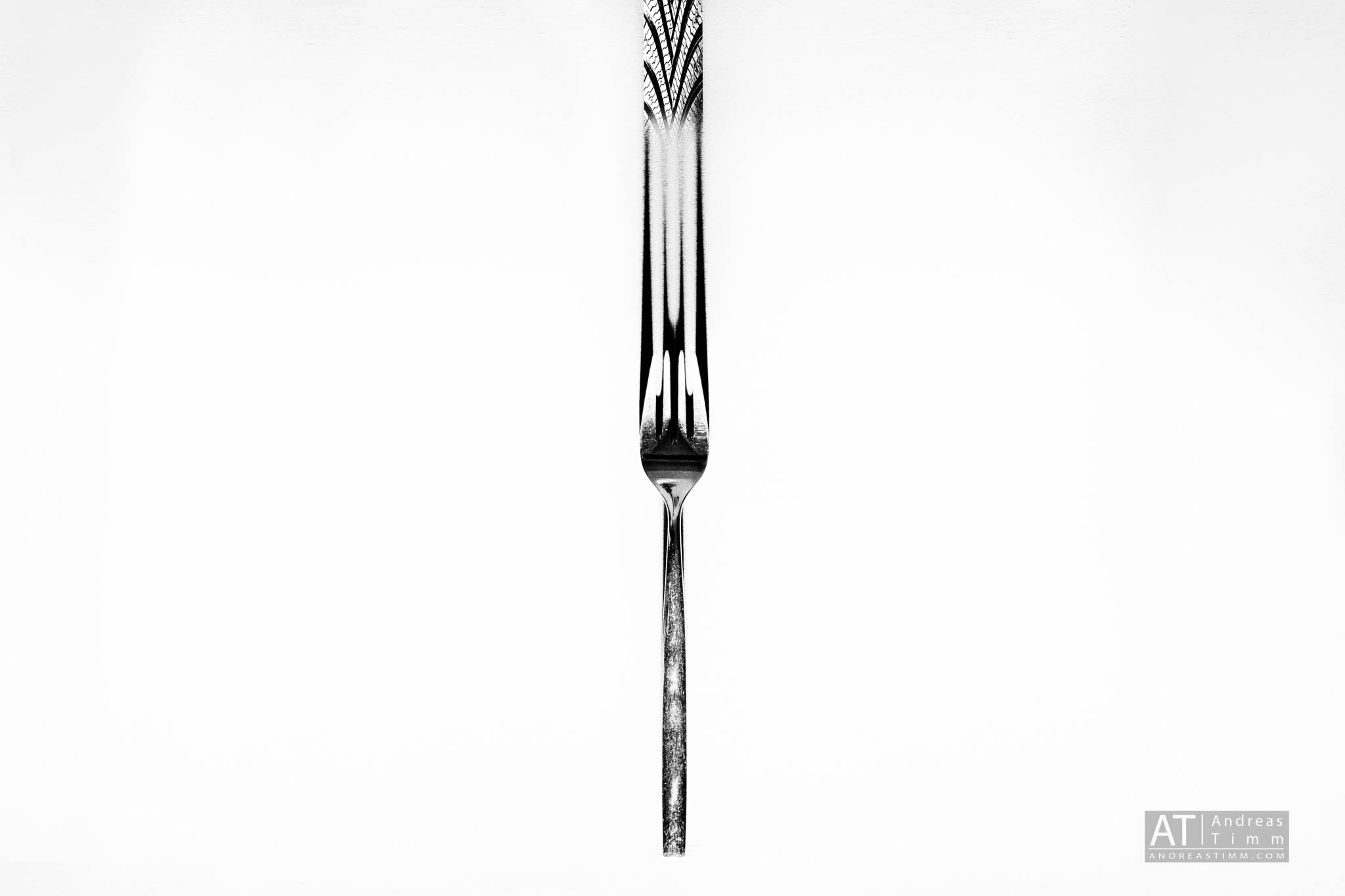 Elegant silver fork with intricate handle design on a plain white background.