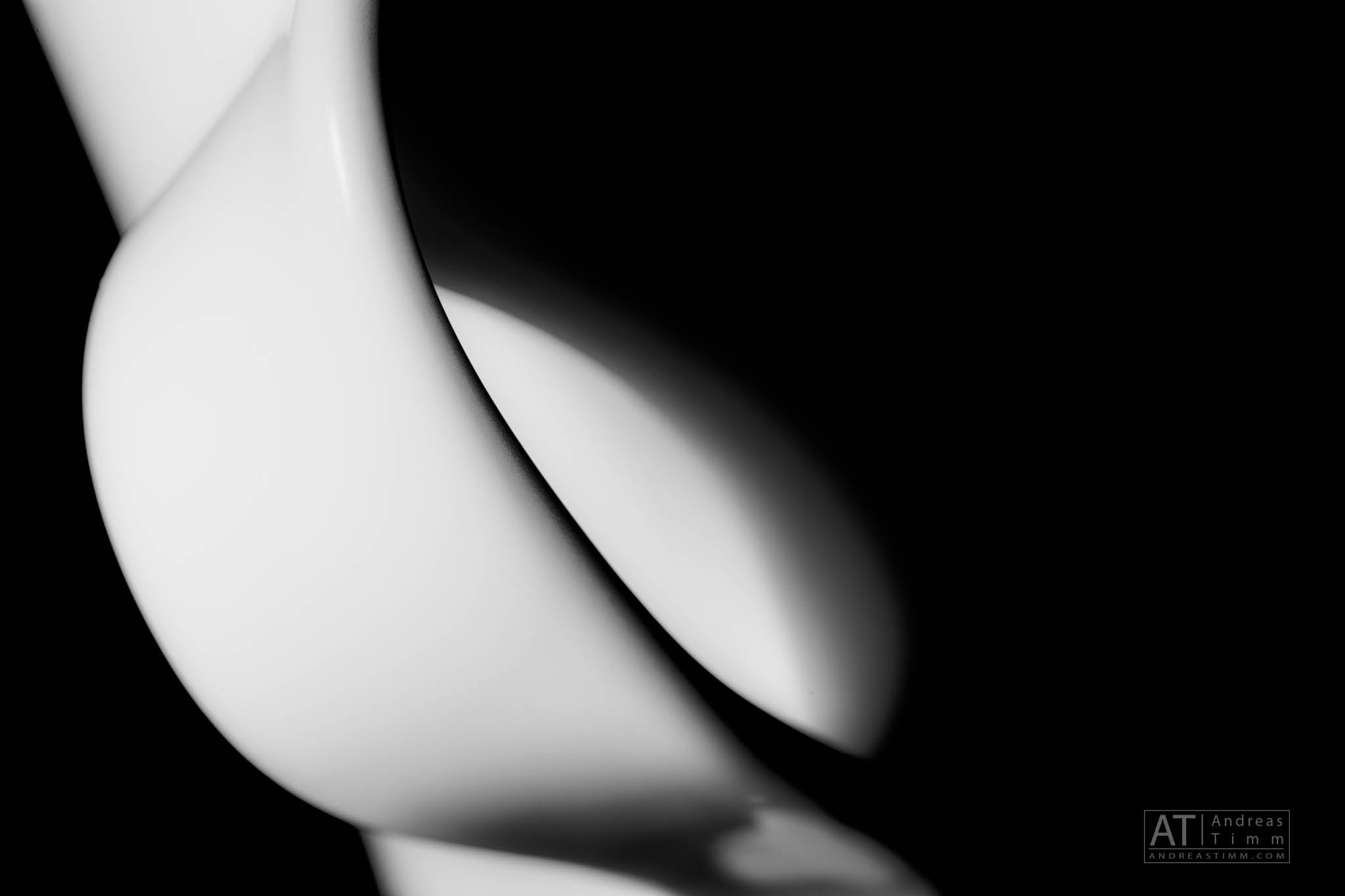 Abstract close-up of white ceramic curves with contrasting shadows against a black background.