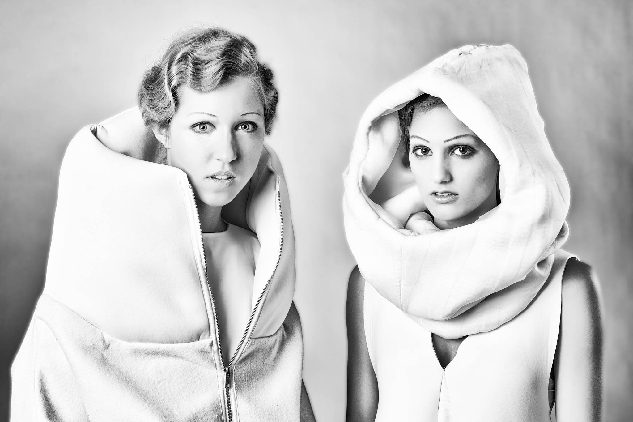 Black and white photo of two women in avant-garde fashion with large, structured collars and futuristic hairstyles.