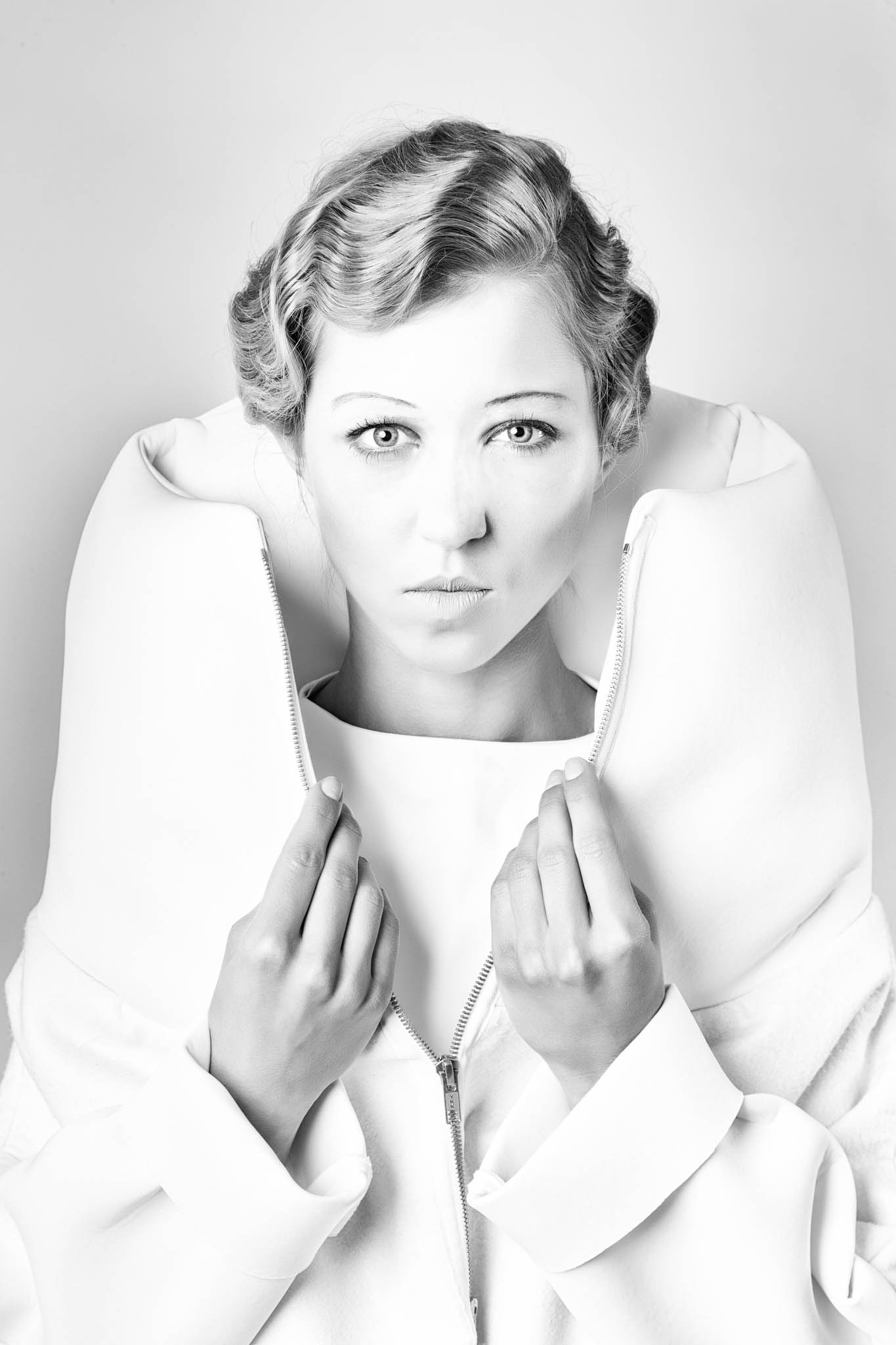 Black and white portrait of a woman in a stylish, zipped high-collar jacket, with a confident expression.