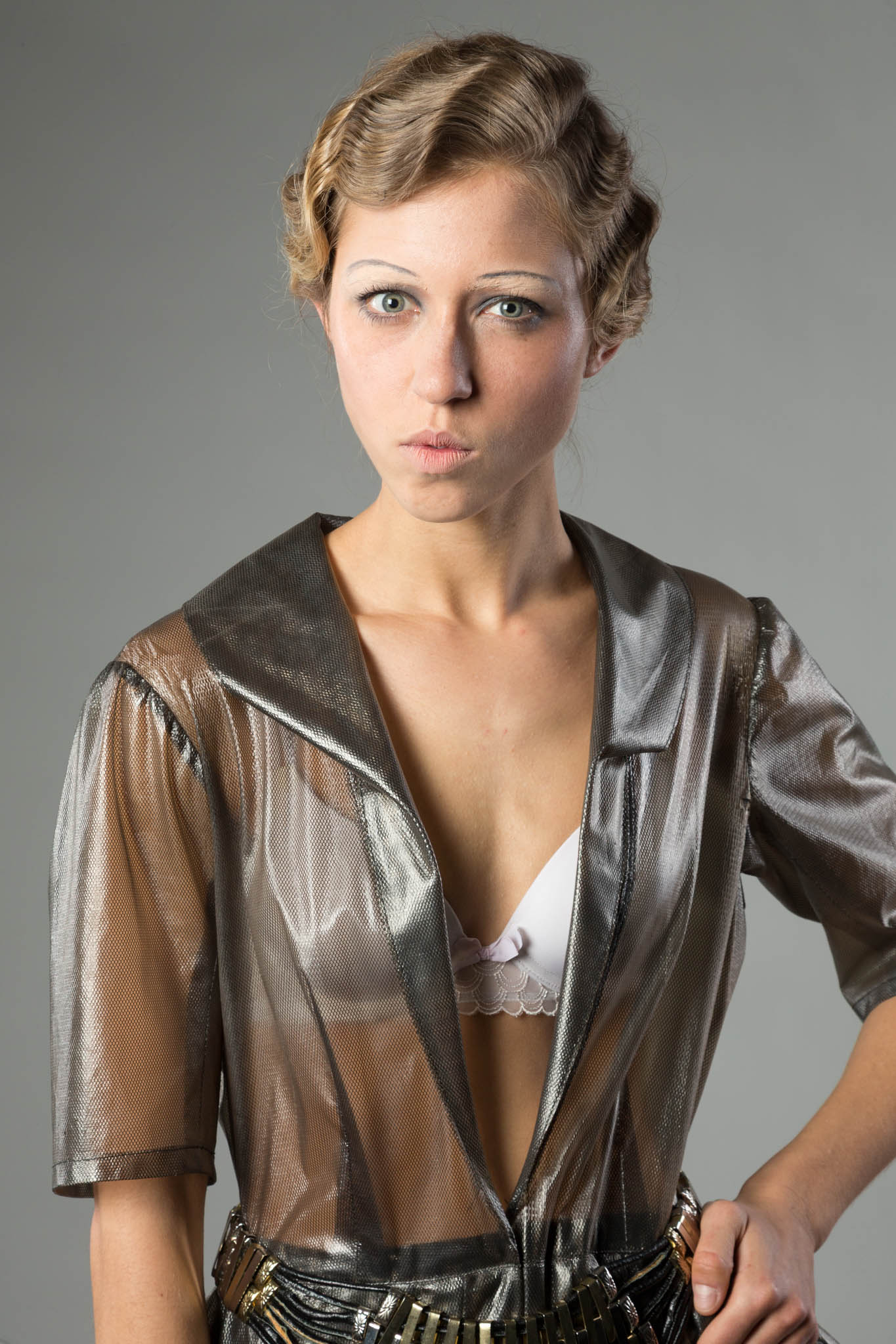 Woman in a metallic mesh dress with vintage hairstyle, posing against a neutral background.