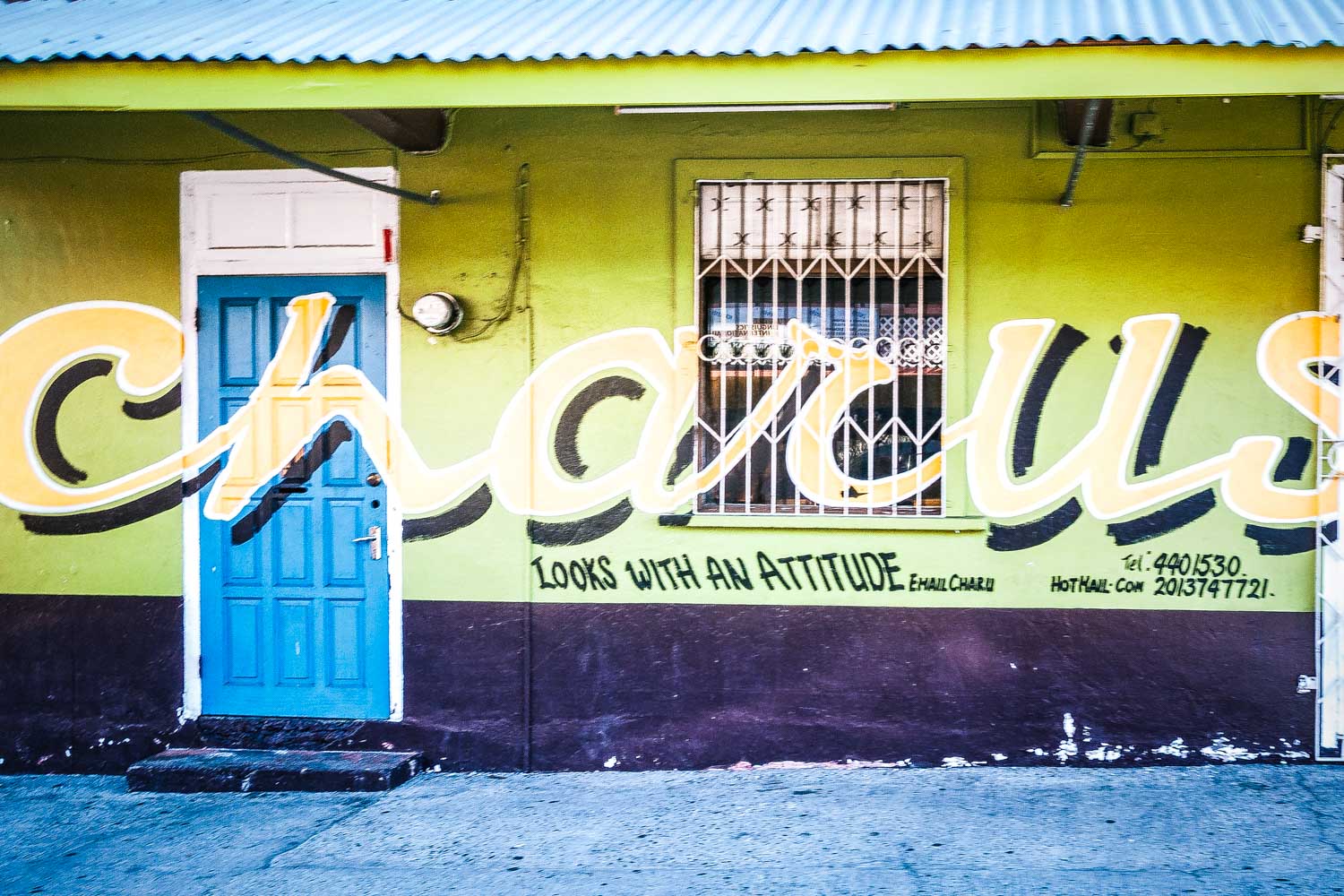 Colorful street mural with bold graffiti text over a blue door and green wall, reading Chaculus Looks with an Attitude.