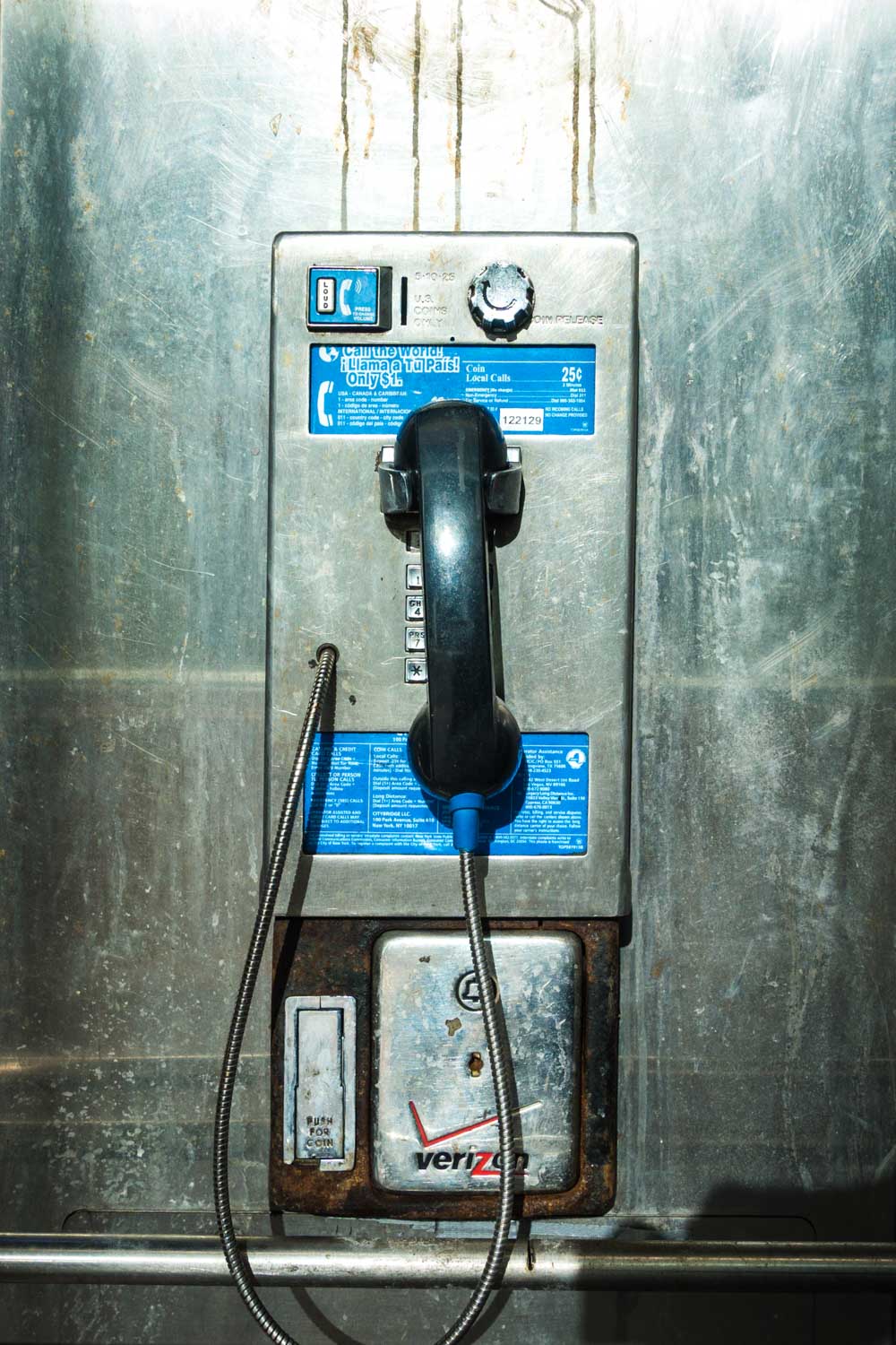 Retro metal payphone with handset and coin slot against a rugged background, showcasing vintage telecommunication.