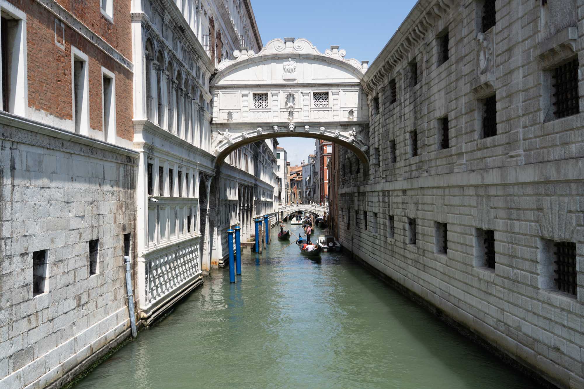 Venice canal with gondolas under the Bridge of Sighs, surrounded by historic buildings on a sunny day.