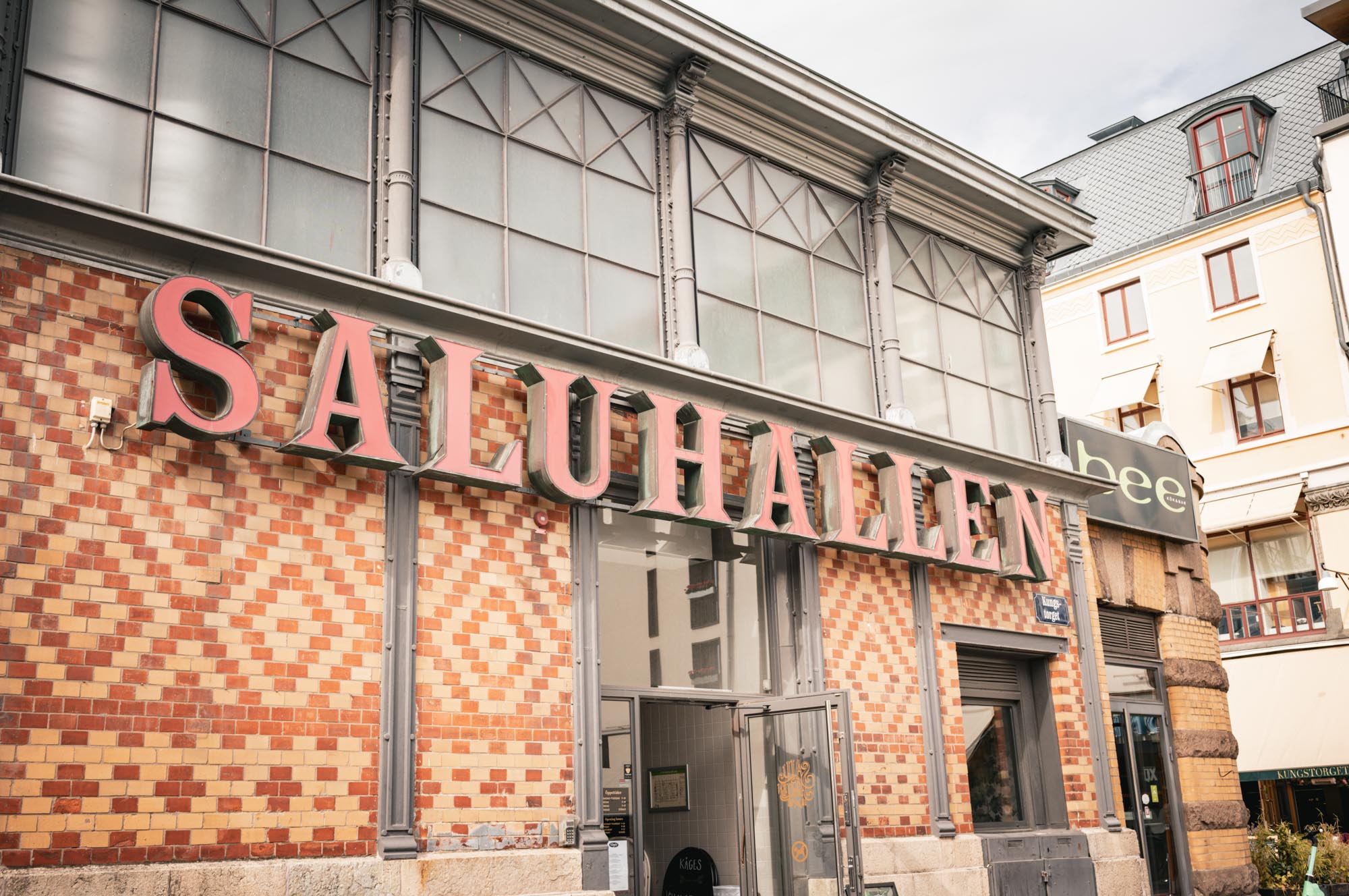 Historic market building Saluhallen with red signage and brick facade, featuring glass windows, Sweden.