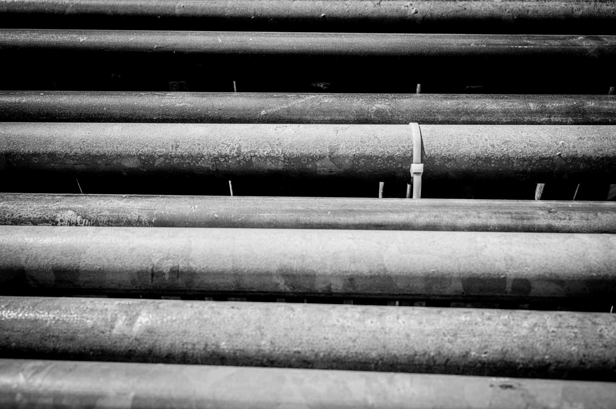 Black and white image of parallel industrial pipes, highlighting texture and symmetry.