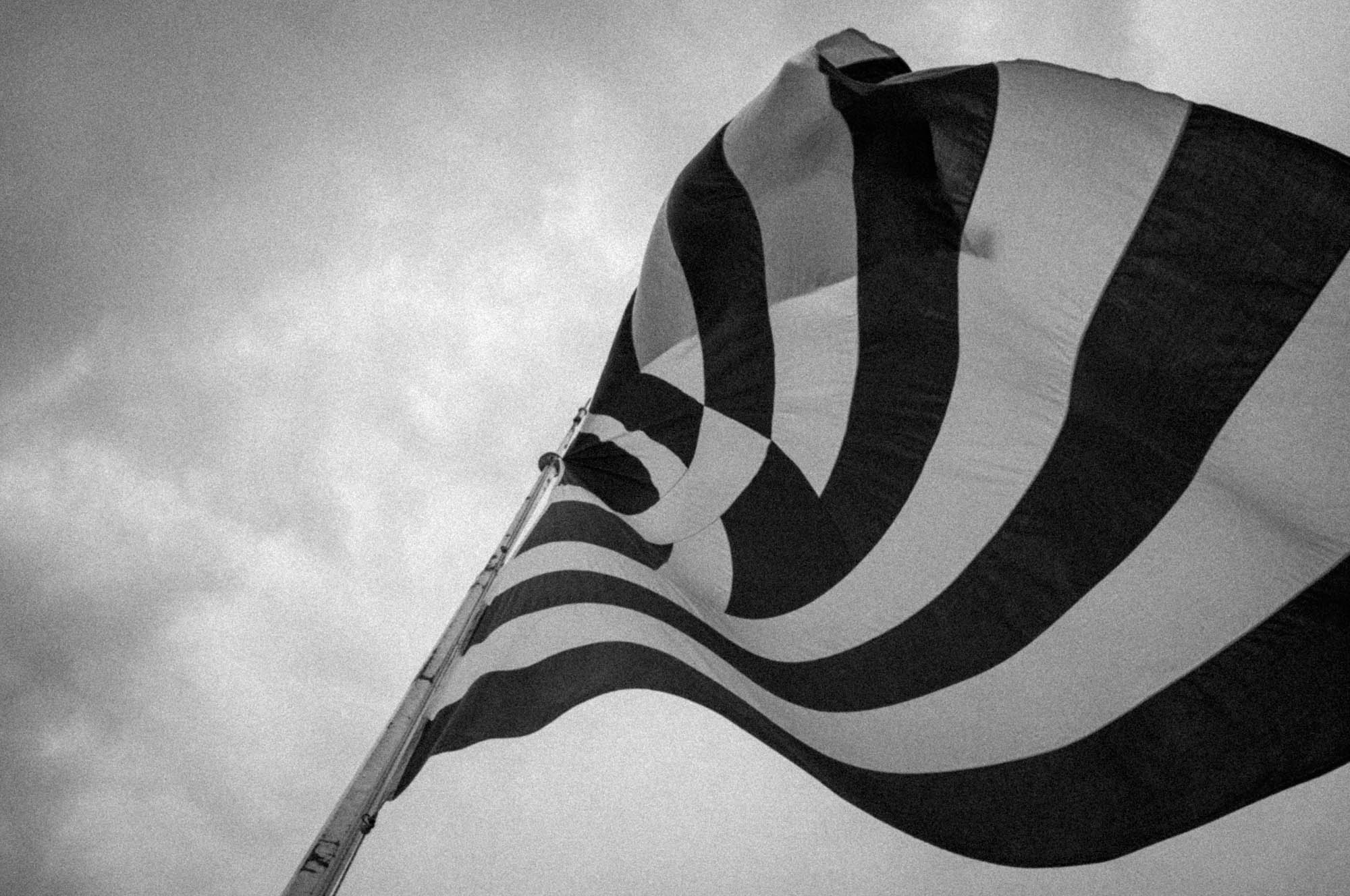 Black and white image of an abstract flag design against a cloudy sky.