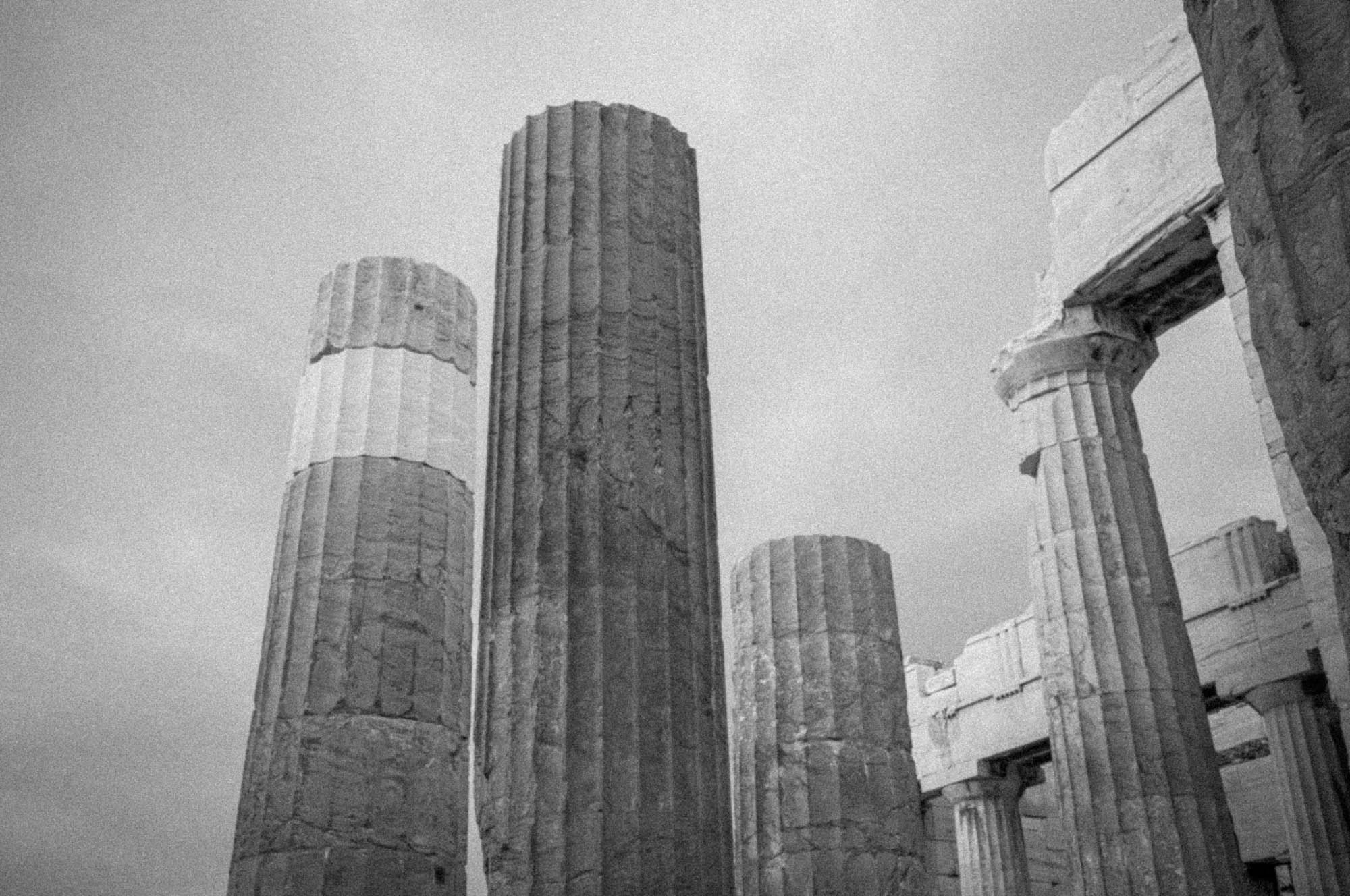 Ancient Greek temple columns under a cloudy sky, showcasing classical architecture and historical grandeur.