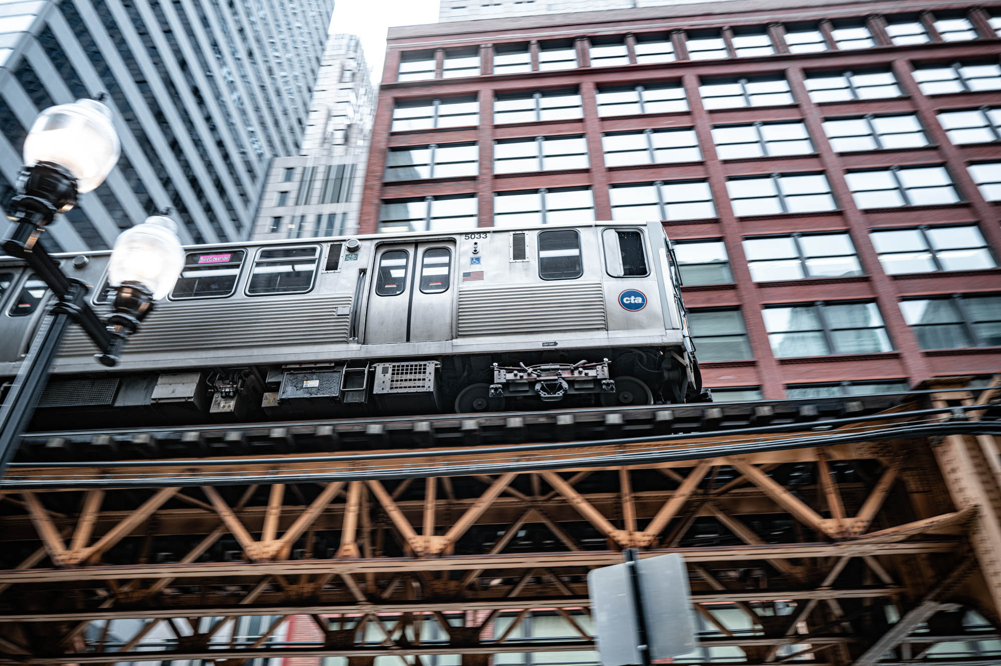 CTA train on elevated tracks in Chicago with city buildings in the background.