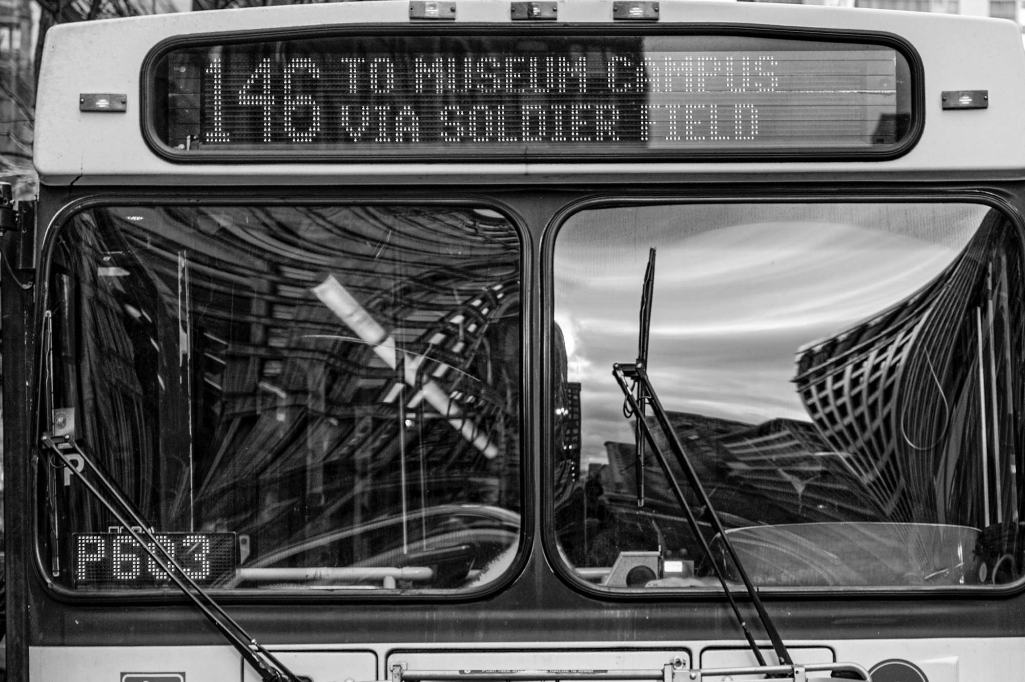 Front view of a bus displaying route 146 to Museum Campus via Soldier Field, with city reflections on the windshield.